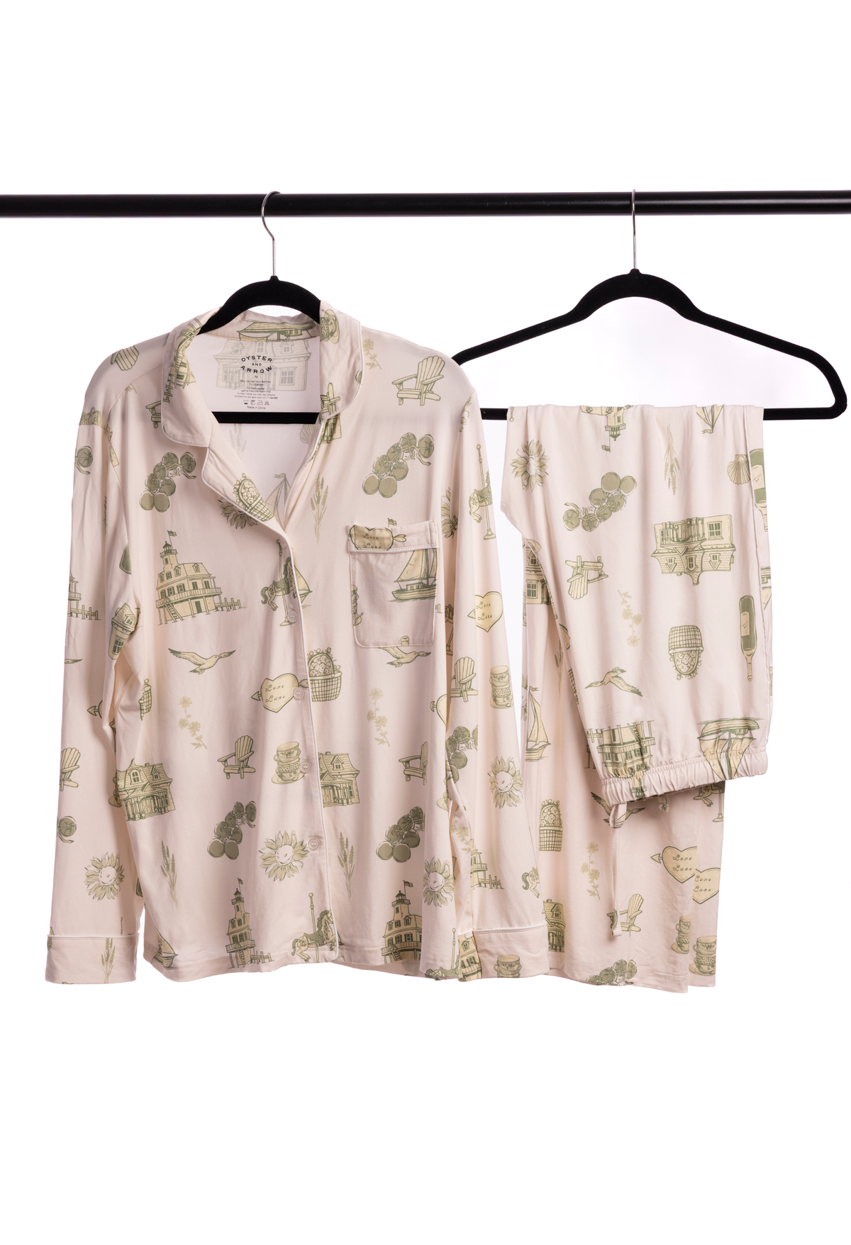 Beige womens toile pajama set with green patterns on hangers against a white background from oyster and arrow