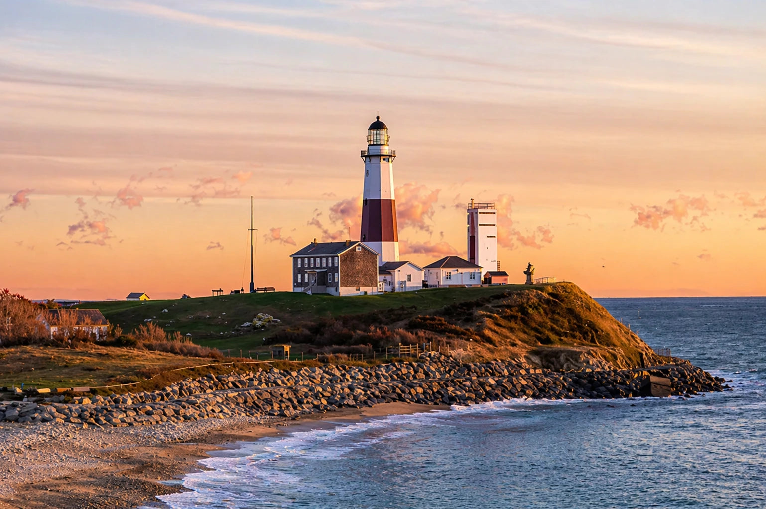 Lighthouse on a hill overlooking the ocean at sunset