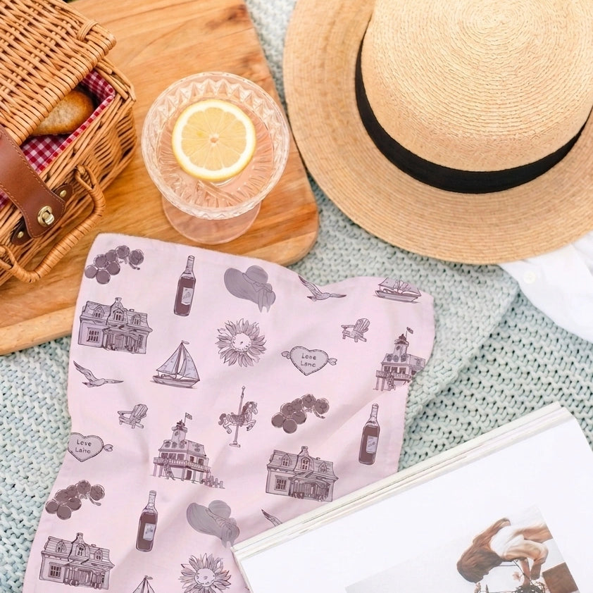 Pink patterned scarf with picnic items including a straw hat, basket, and glass on a blanket.