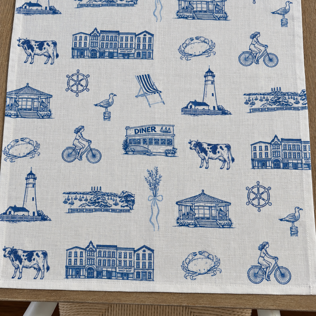 Oyster and Arrow Northport linen napkin featuring a blue and white Cow Harbor toile print with Eaton’s Neck Lighthouse and local Long Island landmarks