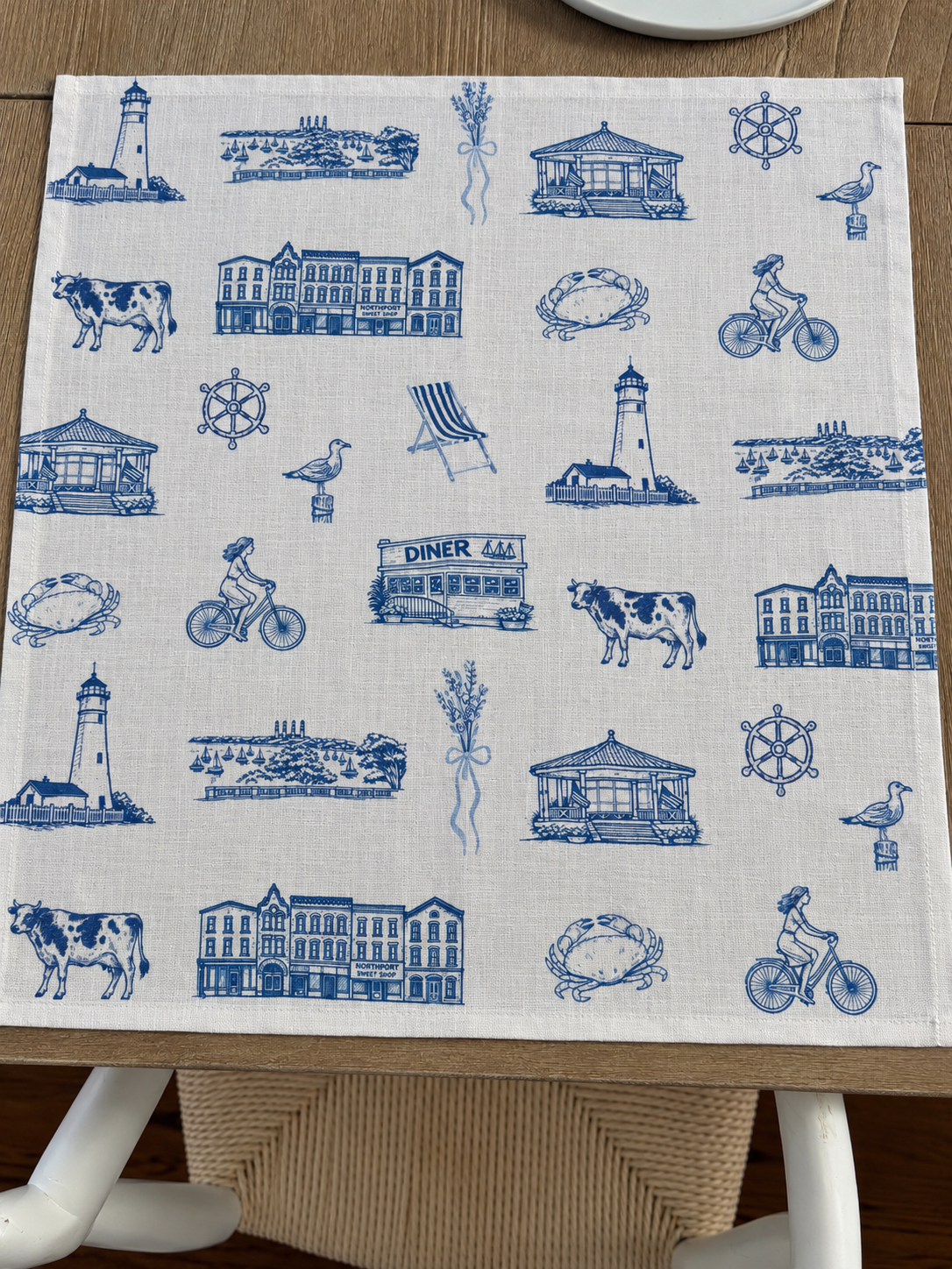 Oyster and Arrow Northport linen napkin featuring a blue and white Cow Harbor toile print with Eaton’s Neck Lighthouse and local Long Island landmarks