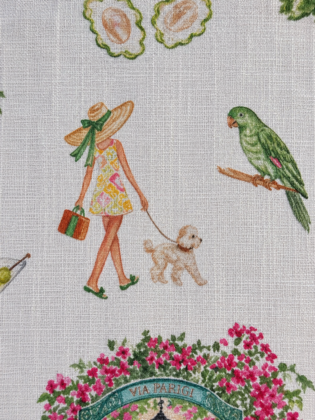 Close-up of Palm Beach linen napkin featuring a 60s inspired lady walking a poodle and a green parrot in a colorfully illustrated print.