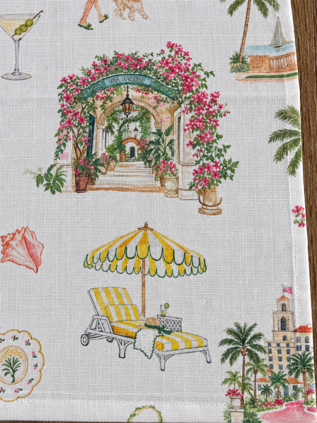 Close-up of Palm Beach linen napkin featuring Via Parigi and a 60s style sun lounger in a colorful illustrated print