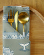 Folded napkin with gold cutlery on a wooden surface