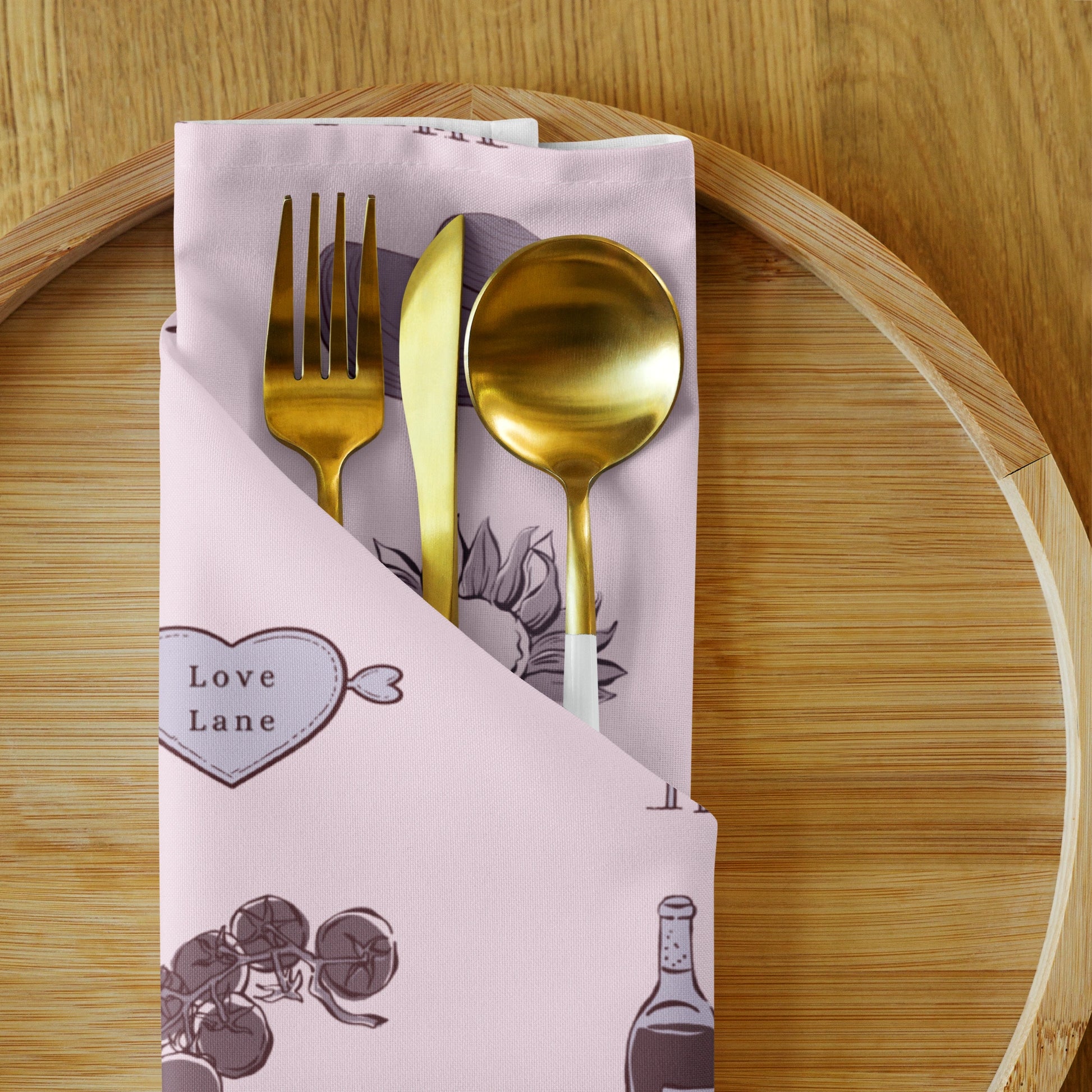 Gold fork, knife, and spoon set in a decorative pink case on a wooden surface