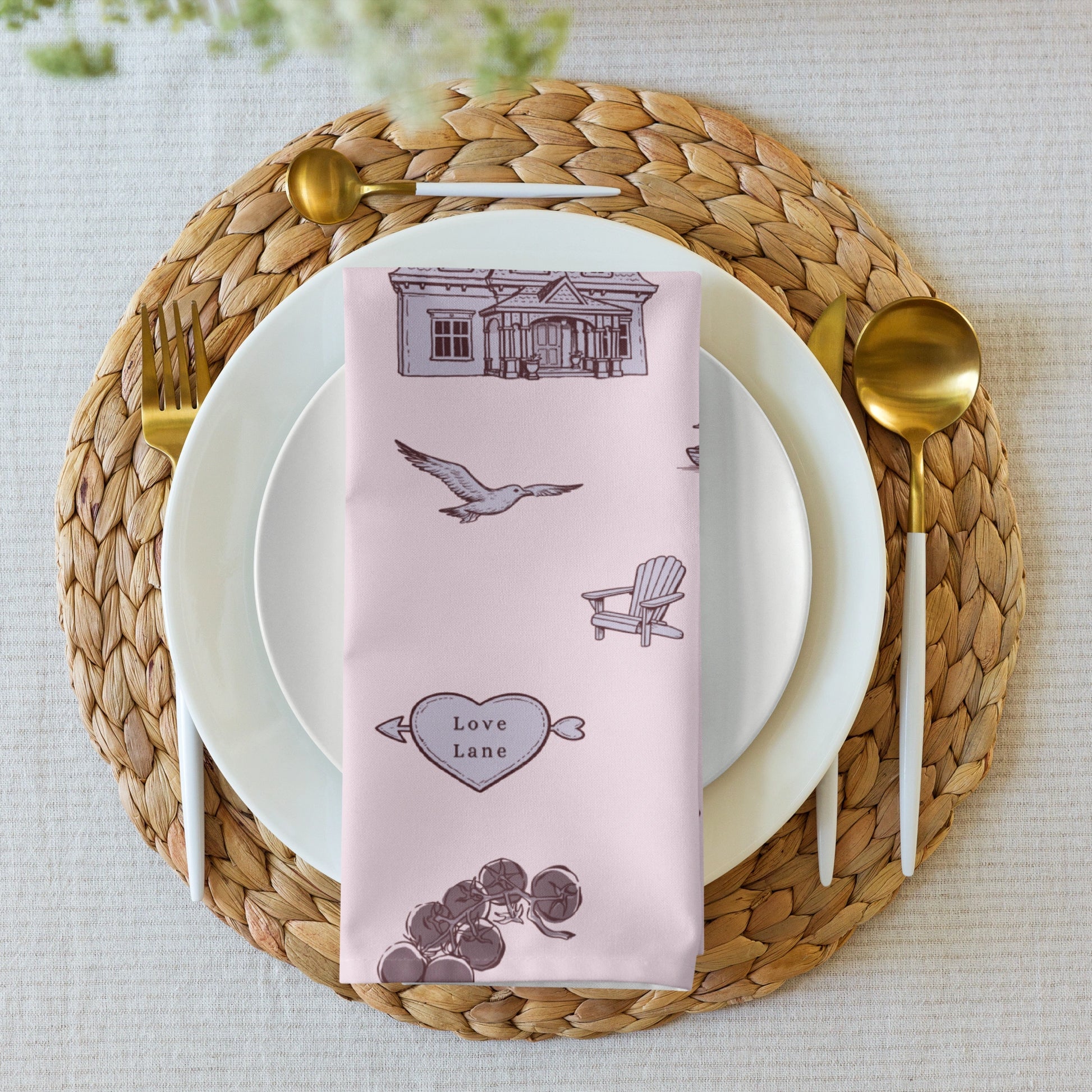 Table setting with a pink napkin featuring illustrations on a woven placemat.